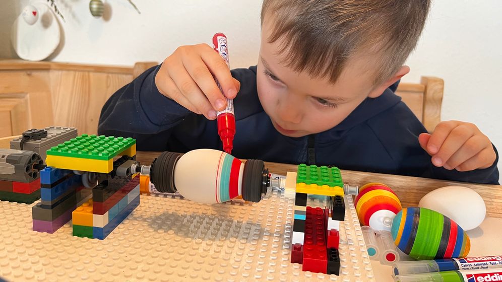 Mit Hilfe einer selbst gebauten Lego-Maschine und Acrylstiften fertigt der Fünfjährige bunte Ostereier.  | Bild:BR/Katharina Reichart