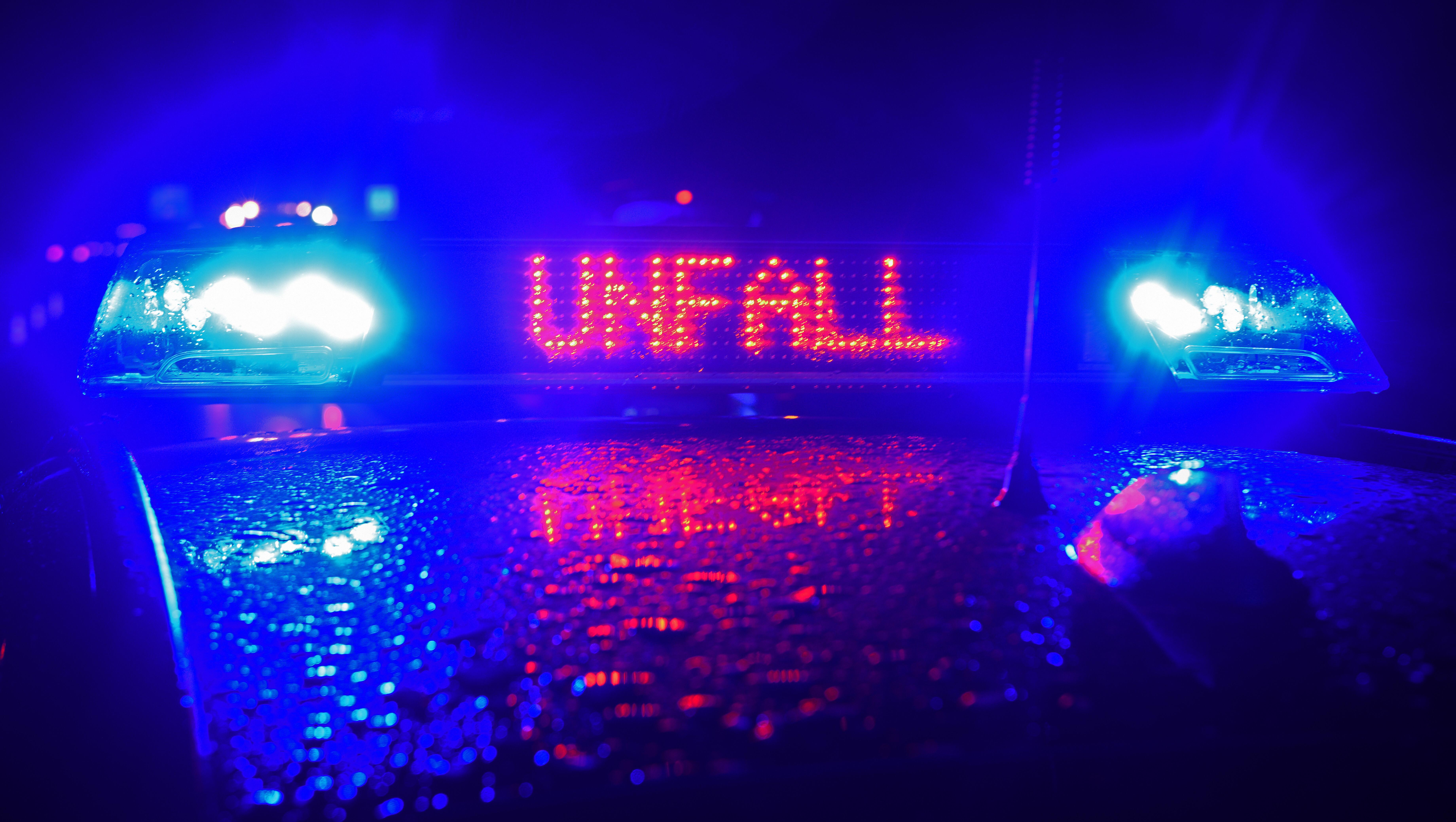 Symbolbild: Auf einem Polizeiwagen leuchtet nachts der Schriftzug "Unfall" auf 