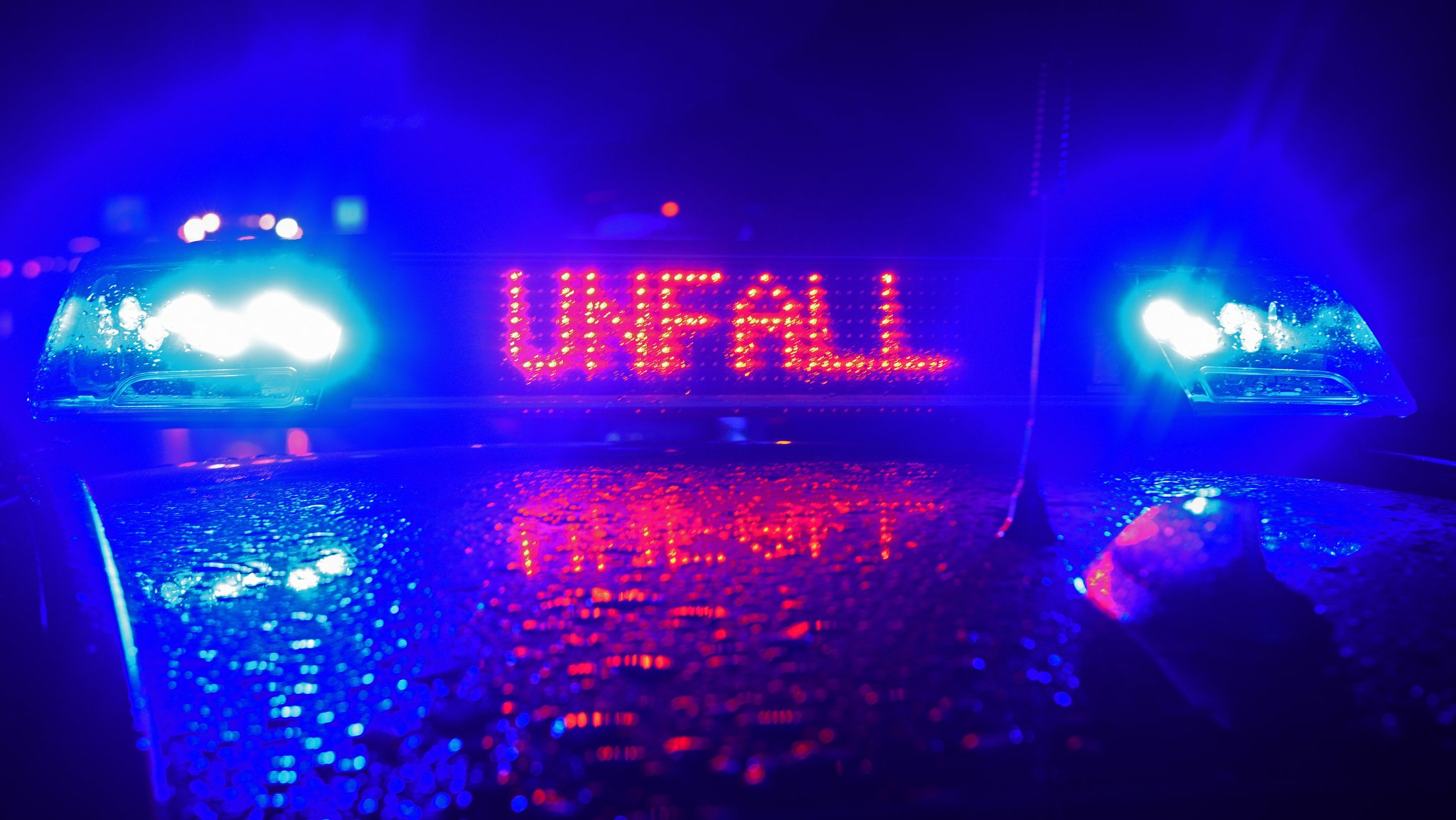 Symbolbild: Auf einem Polizeiwagen leuchtet nachts der Schriftzug "Unfall" auf 