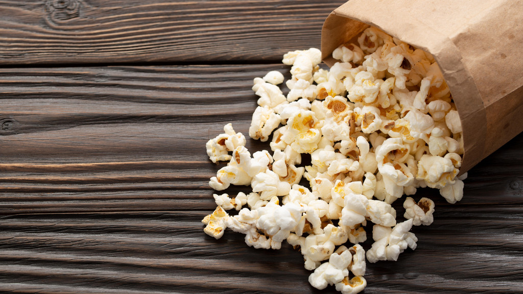 Eine Tüte Popcorn liegt ausgeschüttet auf dem Tisch (Symbolbild)
