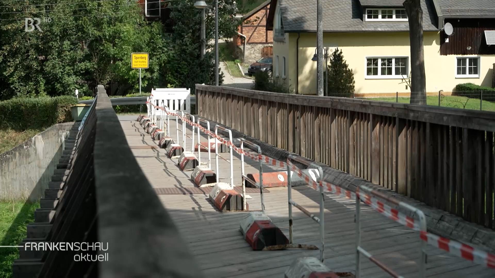 Eine Holzbrücke ist mit rot-weißen Absperrbändern gesperrt. 