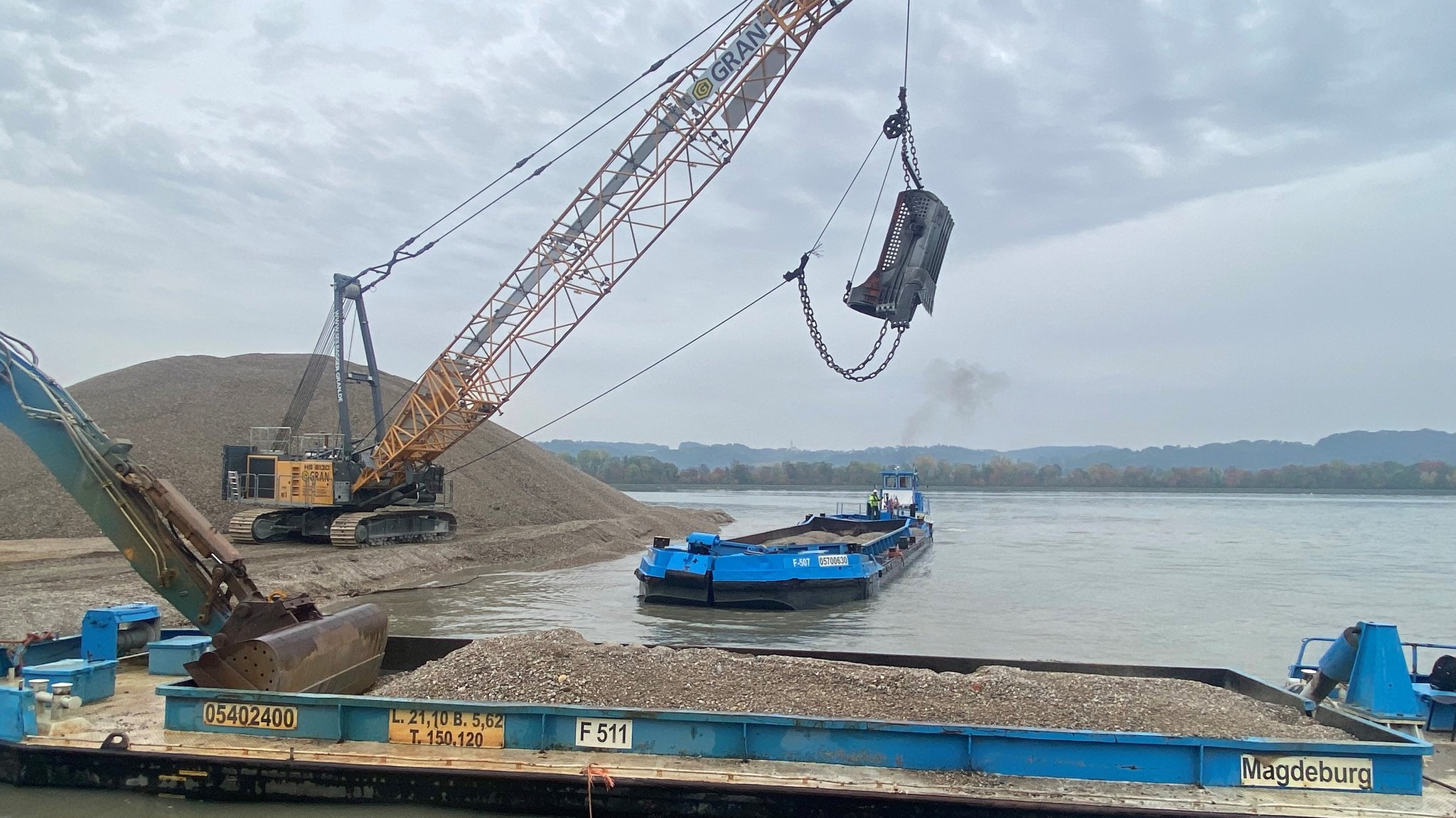 Bagger holen Kies aus der Isar in Landshut.