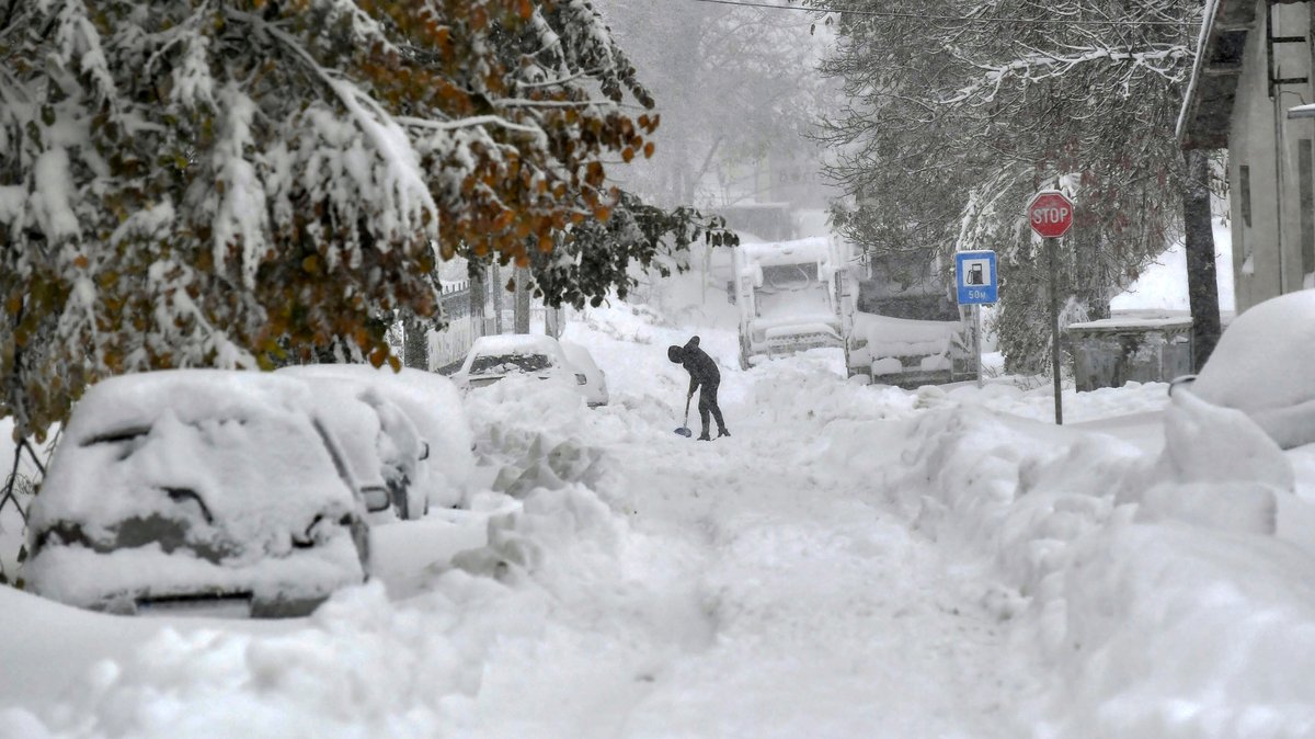 In Isperich in Bulgarien schaufelt ein Mann Schnee von der Straße.