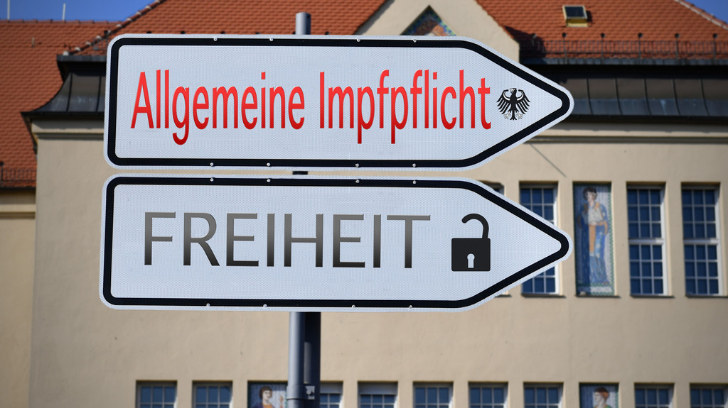 Fotomontage mit zwei Wegweisern mit der Aufschrift "Allgemeine Impfpflicht" und "Freiheit".