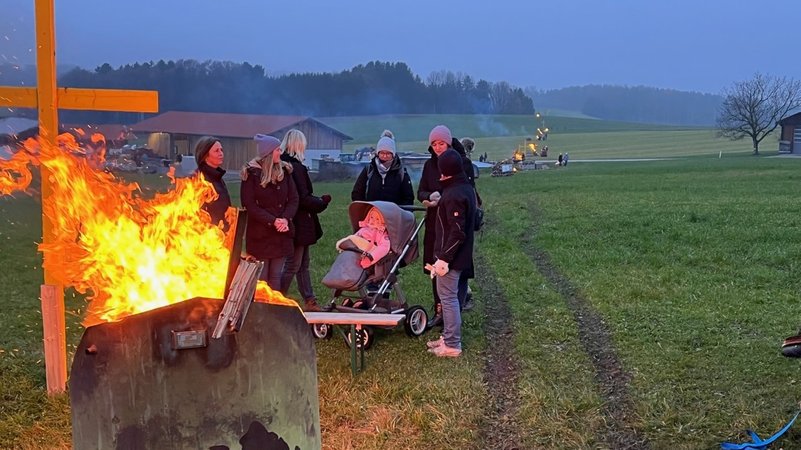 Familien stehen um ein Feuer