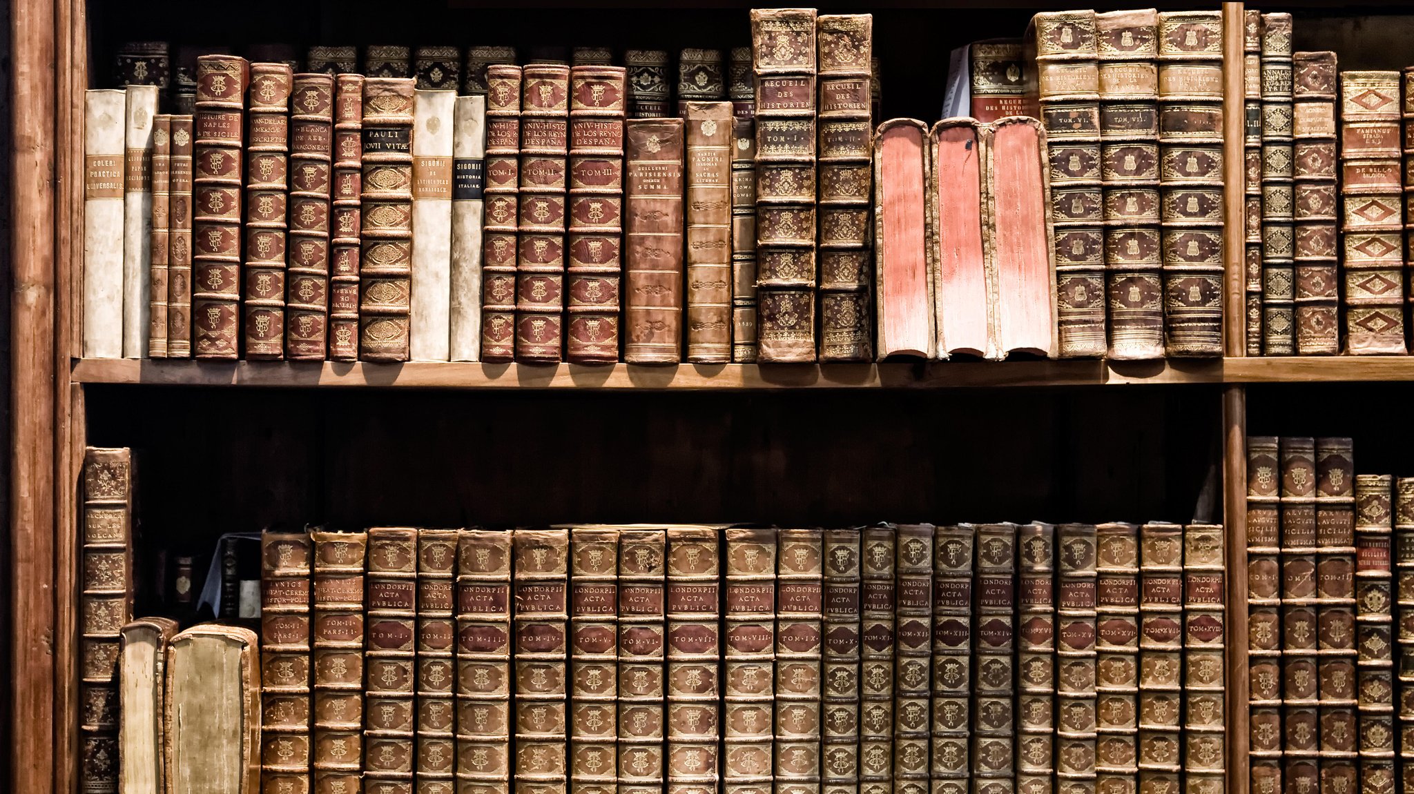 (Symbolbild) Alte Bücher in einem antiken Bücherregal aus Holz. 