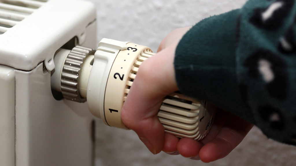 Eine Hand dreht am Temperaturregler einer Heizung (Symbolbild)