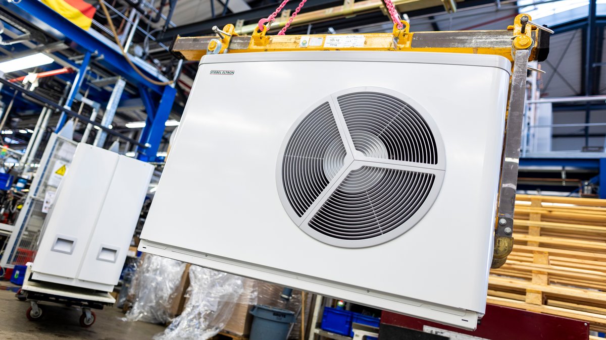 Eine in der Fertigung befindliche Luft-Wasser-Wärmepumpe hängt in einer Werkshalle des Unternehmens «Stiebel Eltron» an einem kleinen Kran.