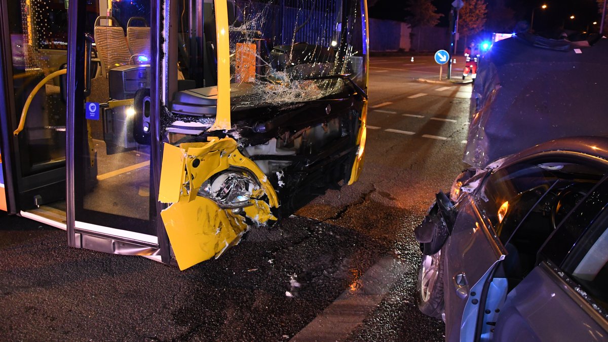 Beschädigter Bus und demoliertes Auto an einer Kreuzung