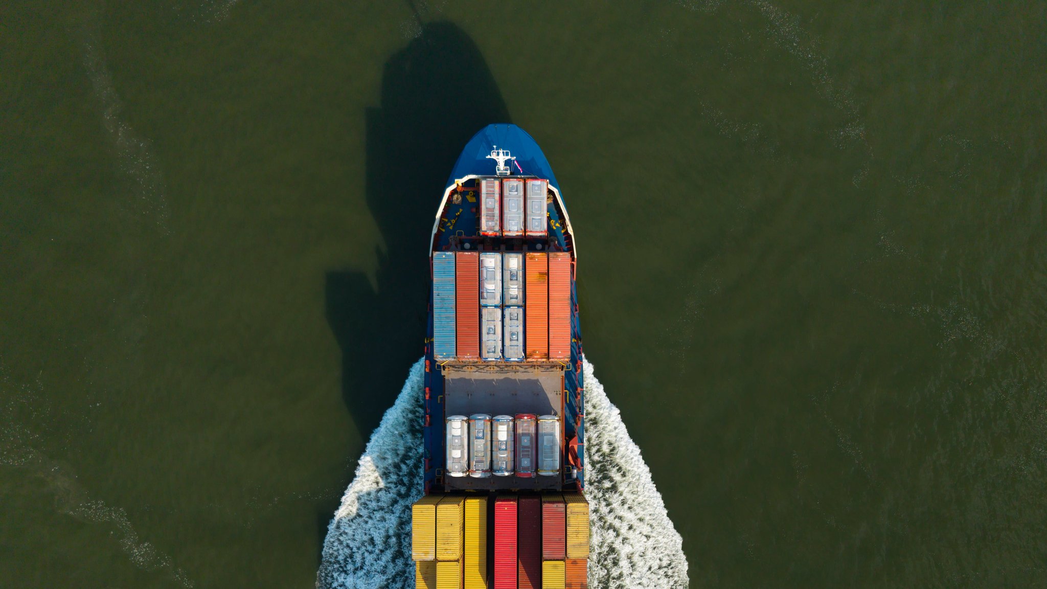 Ein mit bunten Containern beladener Frachter fährt auf einen niederländischen Hafen zu. | Bild: dpa/pa/Westend61/Mischa Keijser Ein mit bunten Containern beladener Frachter fährt auf einen niederländischen Hafen zu.