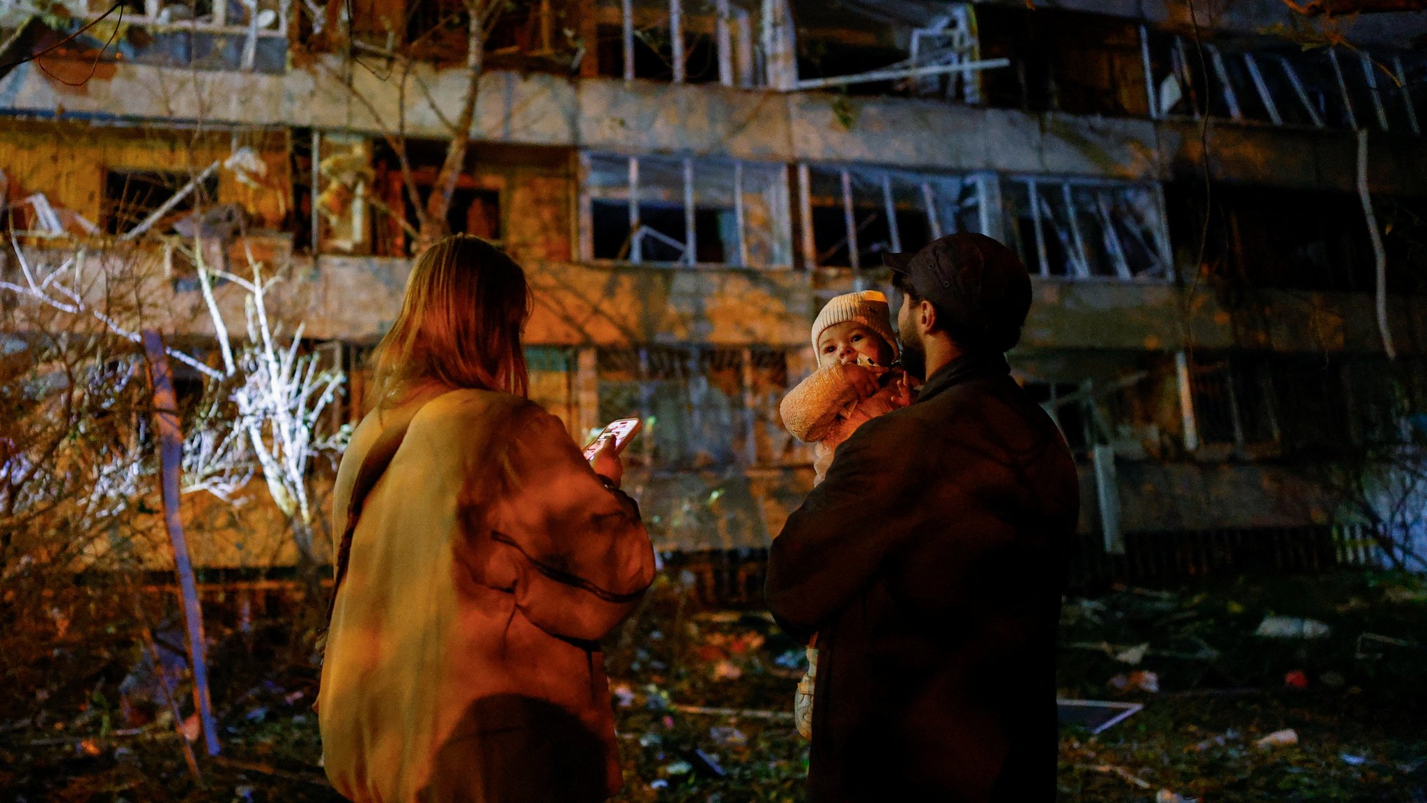 Eine ukrainische Familie vor ihrem zerstörten Haus in Kiew. Landesweit fiel nach Angriffen in 600.000 Haushalten der Strom aus. | Bild: REUTERS/Valentyn Ogirenko Eine ukrainische Familie vor ihrem zerstörten Haus in Kiew. Landesweit fiel nach Angriffen in 600.000 Haushalten der Strom aus.