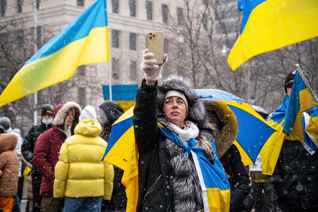 Eine Demonstrantin auf einer Ukraine-Demo hält ihr Handy in die Höhe.