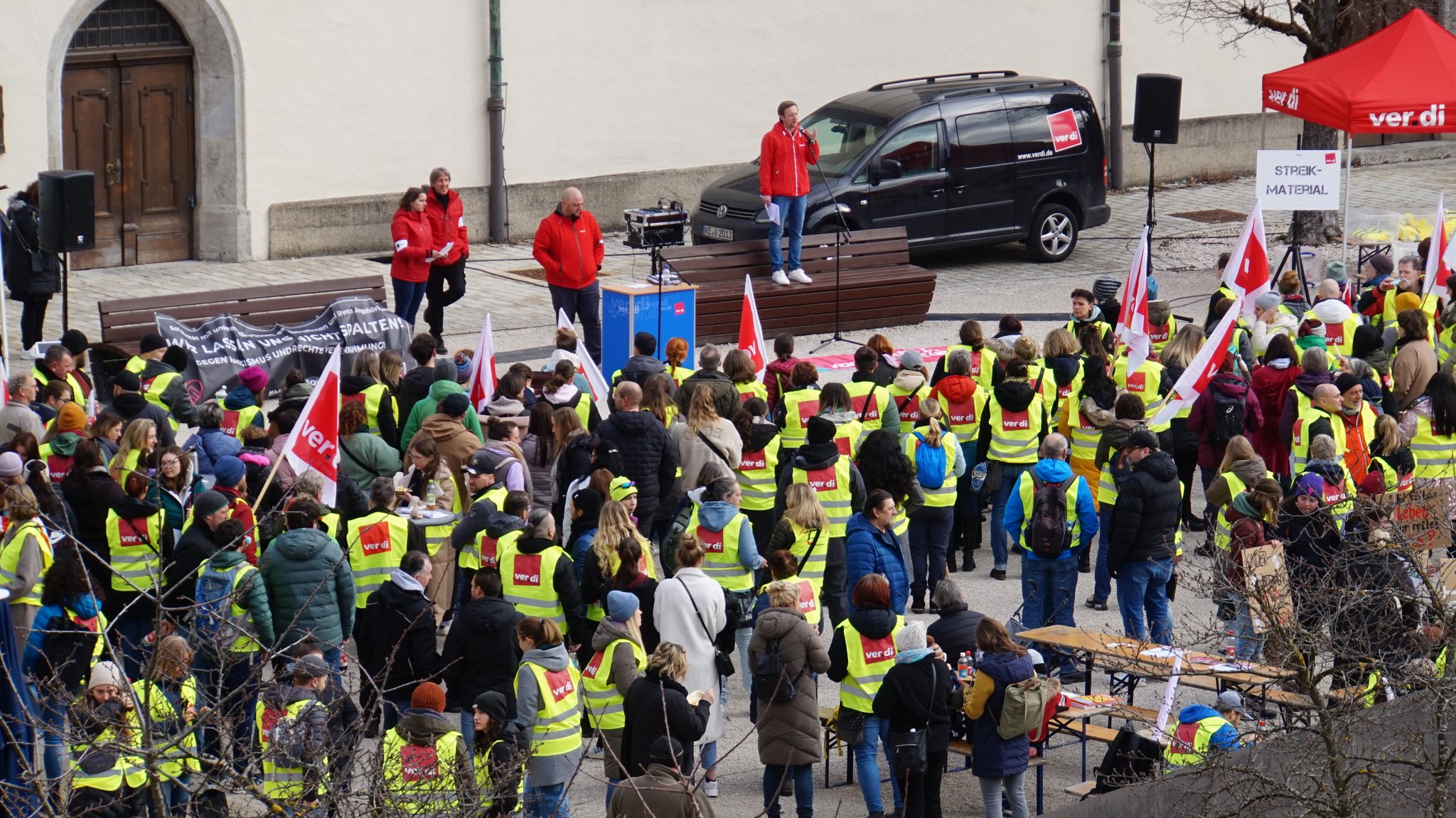 Menschen in gelben Verdi-Warnwesten stehen mit Fahnen und Plakaten bei der Kundgebung in Kempten.