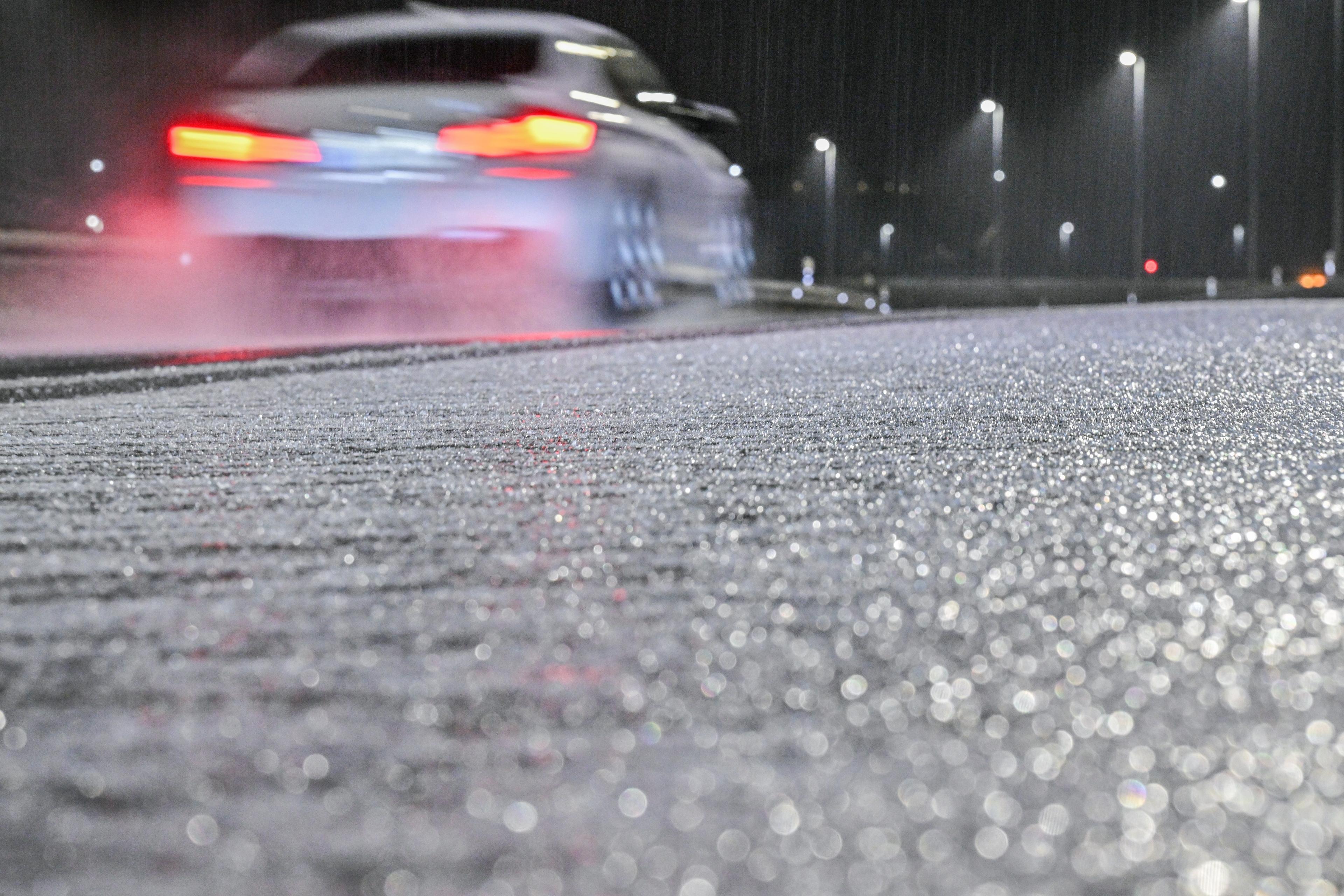 24.11.2025: Ein Auto fährt in der Nähe des Flughafens München an Eis auf einer Straße vorbei.