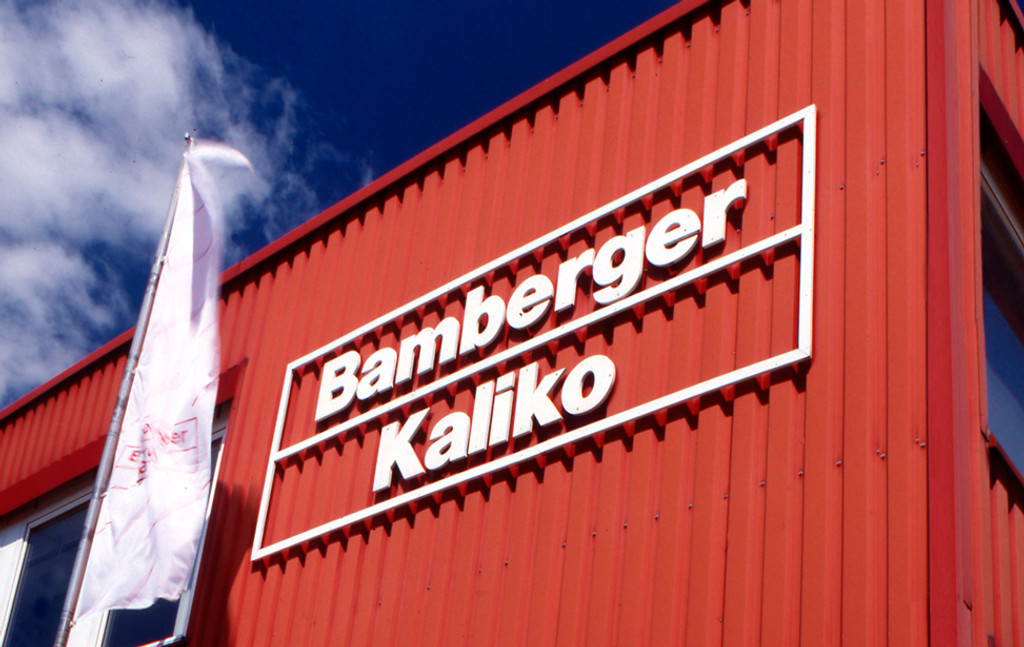 "Bamberger Kaliko" steht in weißen Buchstaben auf einer roten Gebäudefassade.