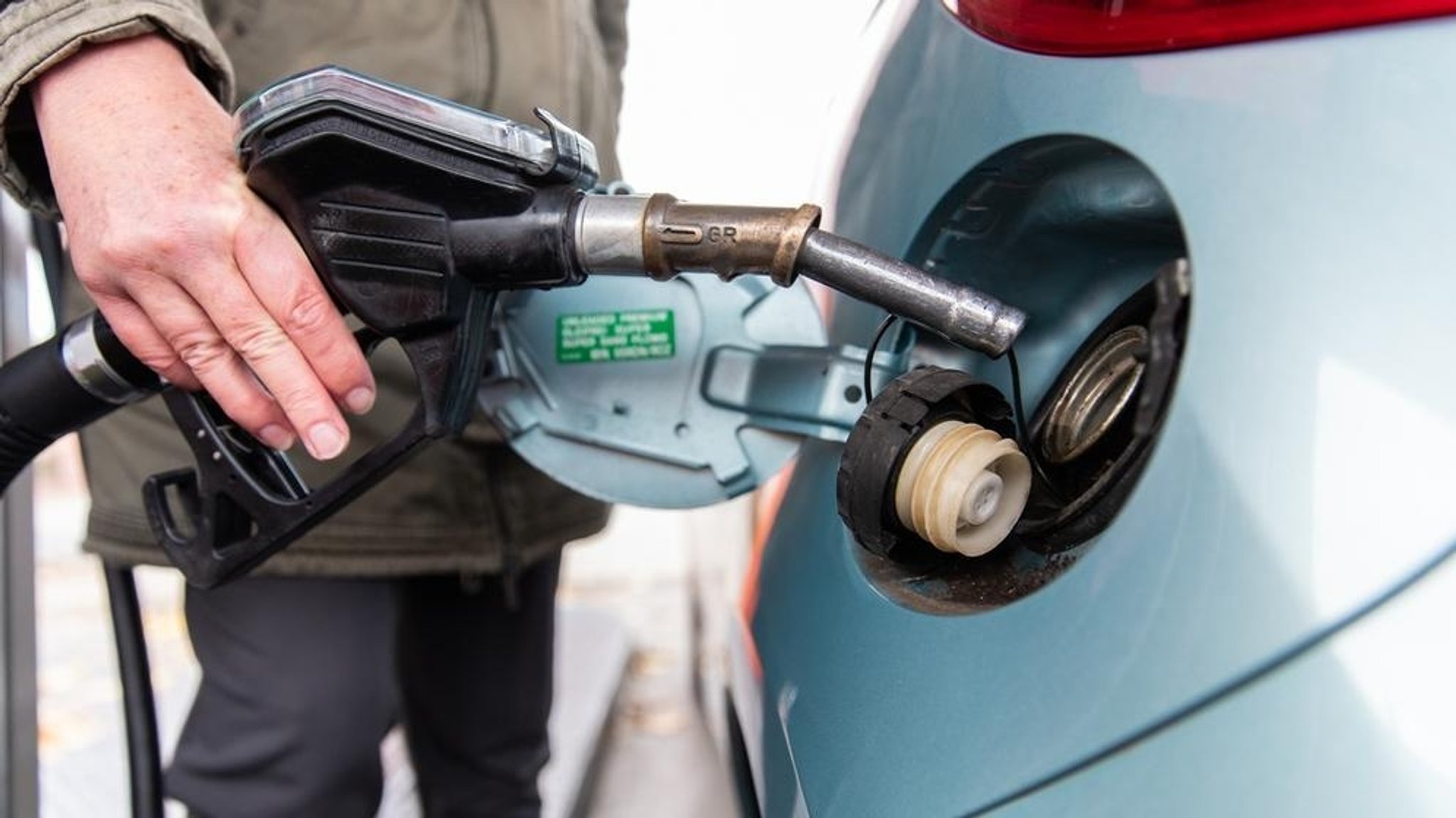 Eine Frau tankt ihr Auto an einer Tankstelle auf.