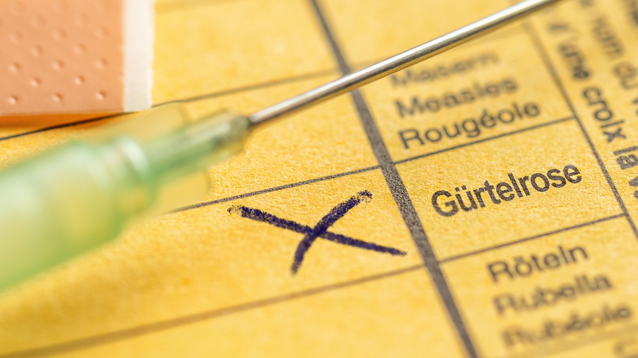 Impfpass mit Eintrag "Gürtelrose" und eine Spritze