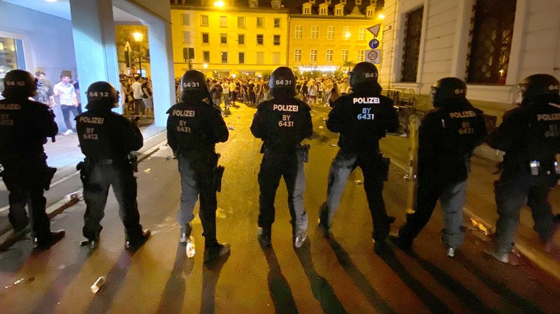 Polizisten stehen in der Augsburger Innenstadt, wo sich Menschen zum Feiern versammelt haben. 