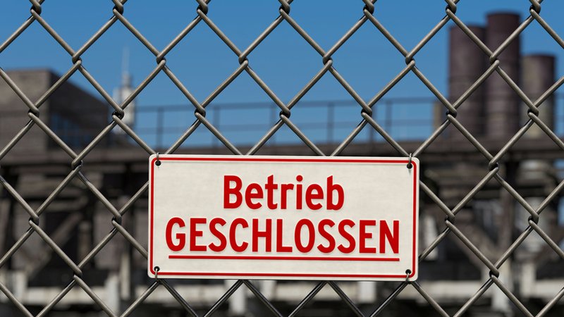An einem Gitterzaun hängt ein Schild mit der Aufschrift "Betrieb GESCHLOSSEN" | Bild: stock.adobe.com/bluedesign An einem Gitterzaun hängt ein Schild mit der Aufschrift "Betrieb GESCHLOSSEN"