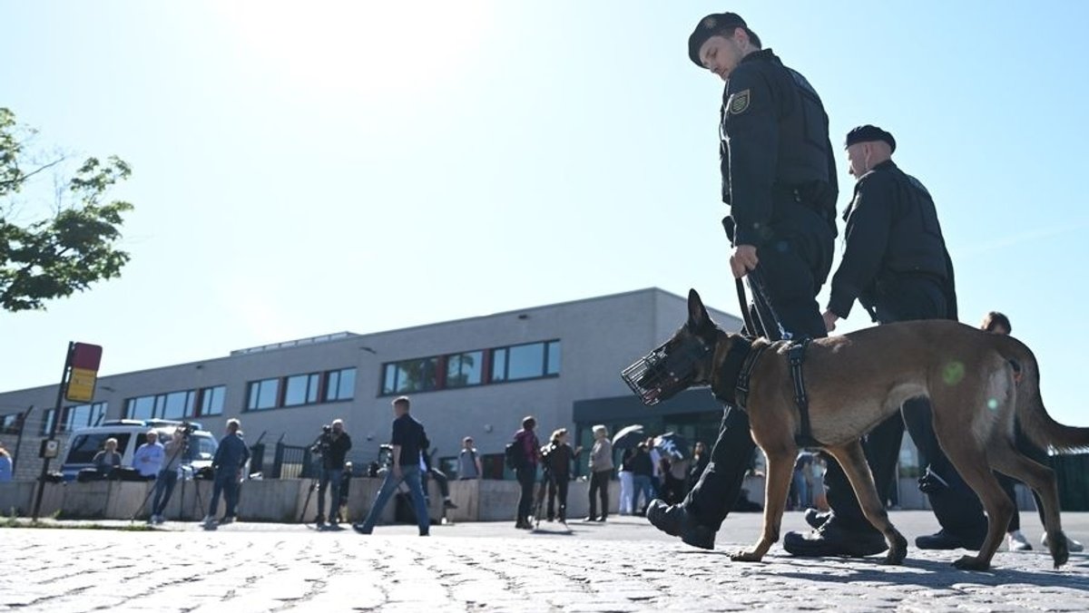 Polizisten laufen mit einem Spürhund vor dem Oberlandesgericht (OLG) Dresden entlang