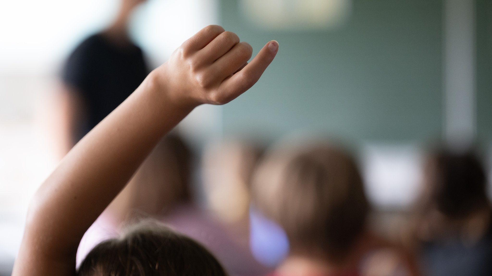 Schülerinnen und Schüler einer vierten Klasse einer Grundschule nehmen am Unterricht teil, eine Schülerin meldet sich.