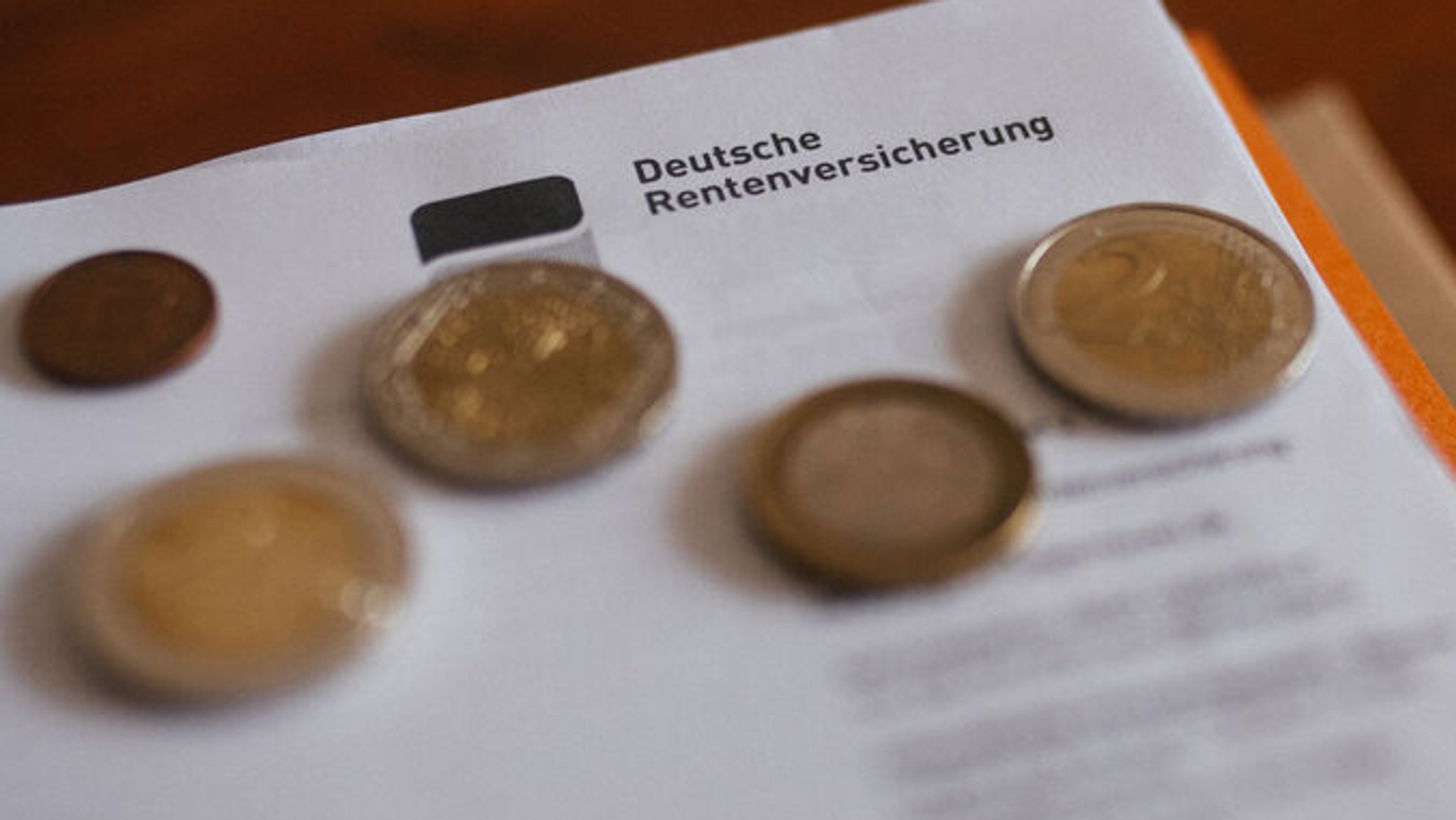 Ein Brief der Deutschen Rentenversicherung in einem Ordner mit Geld.