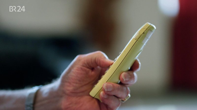 Eine Hand hält ein Telefon. | Bild: BR Eine Hand hält ein Telefon.