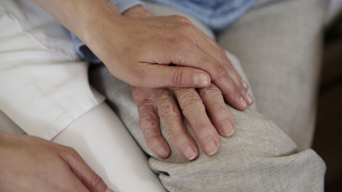 Symbolbild: Medizinisches Personal hält die Hand einer älteren Person.