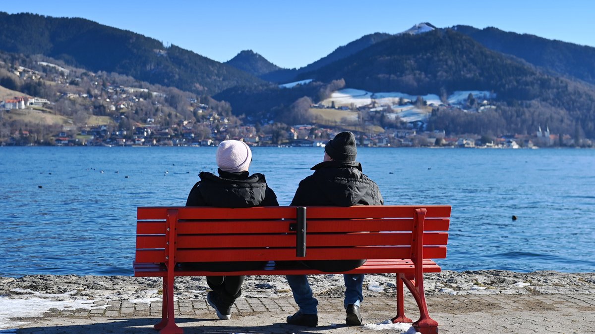 Zwei Senioren sitzen auf einer Bank mit Blikc auf den Tegernsee