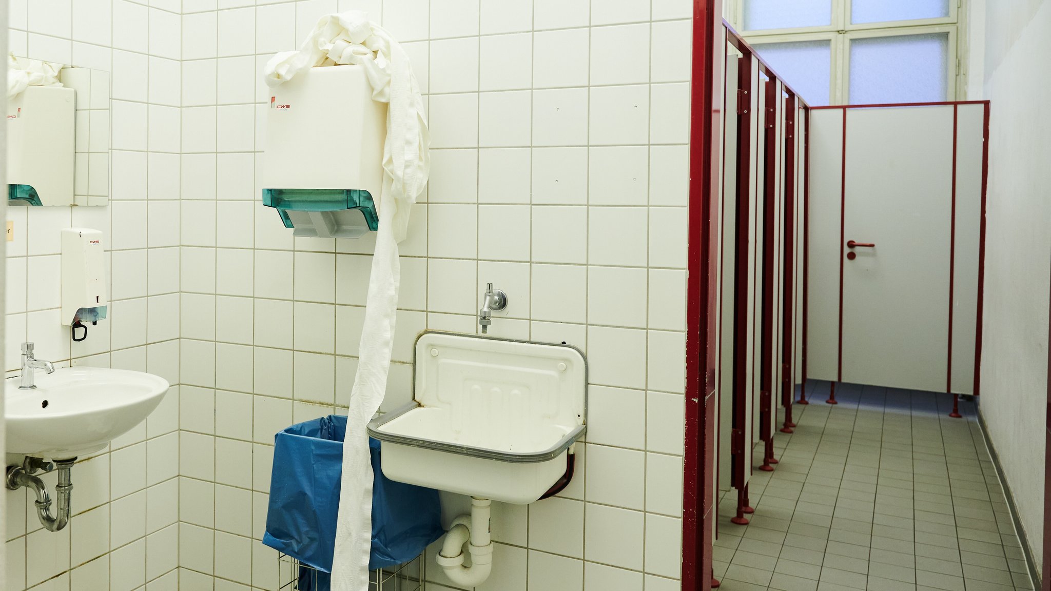 In einer Schultoilette fällt die benutzte Handtuchrolle vom Handtuchspender auf den Boden. | Bild: pa//dpa | Annette Riedl In einer Schultoilette fällt die benutzte Handtuchrolle vom Handtuchspender auf den Boden.