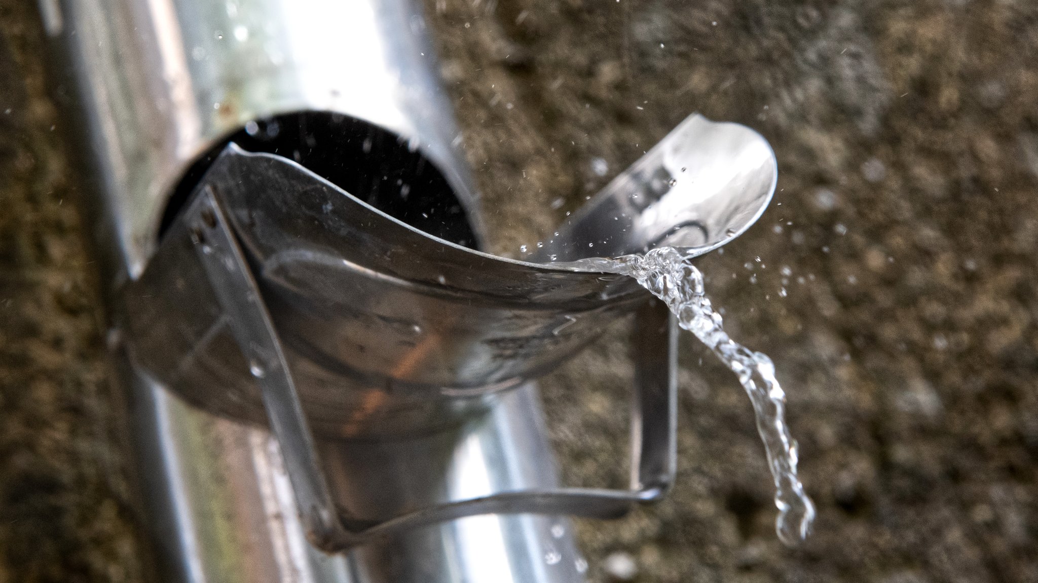 Regenwasser, das aus einer Öffnung in der Regenrinne fließt