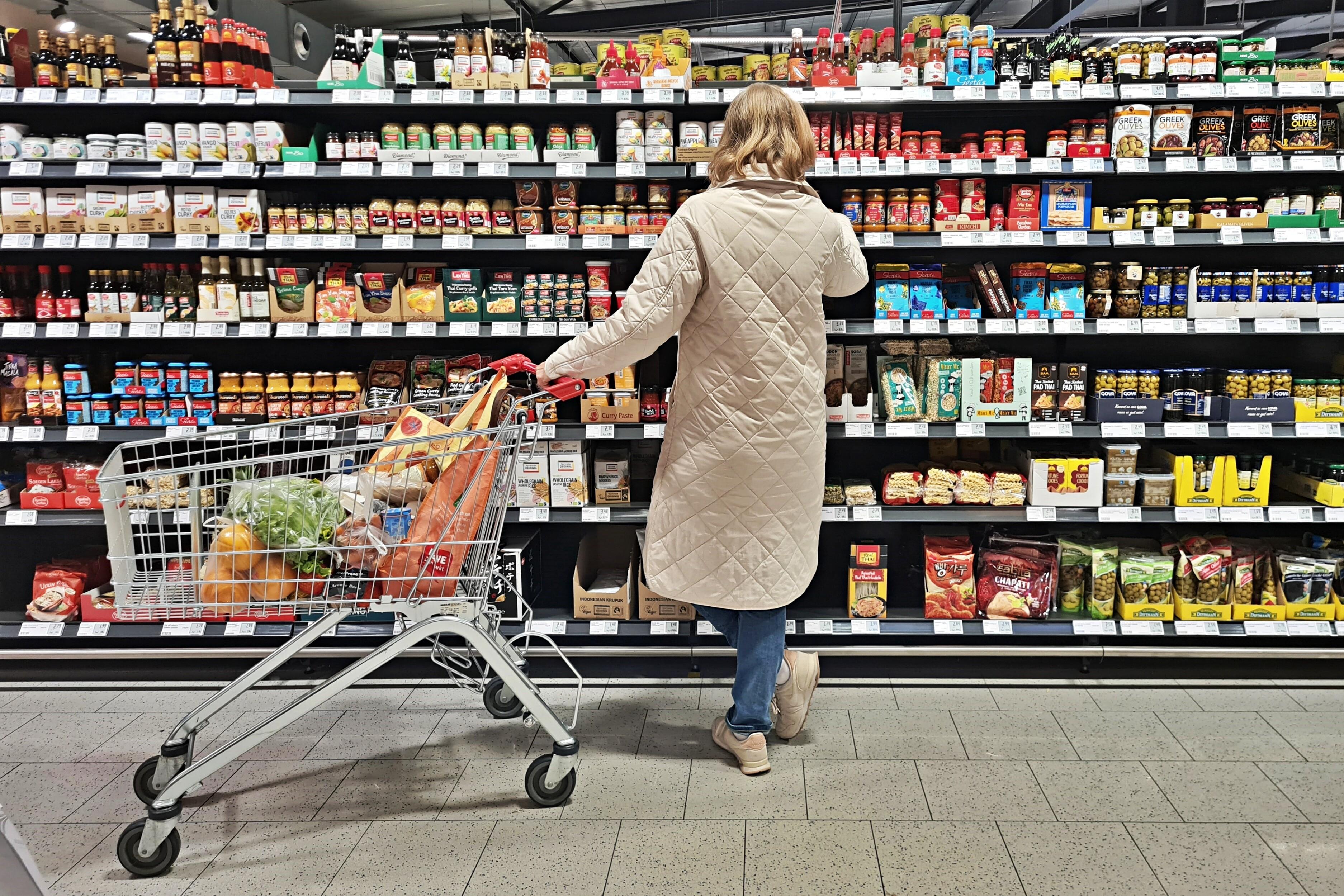 Symbolbild "Handel / Konsum": Kundin mit Einkaufswagen in einem Supermarkt