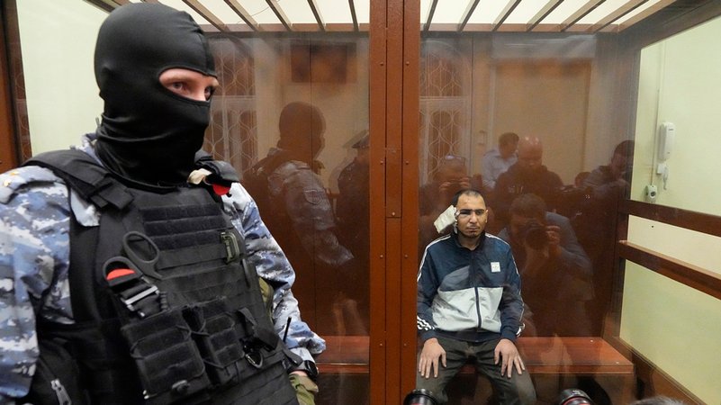 Ein Tatverdächtiger des Terroranschlags auf die Konzerthalle Crocus City Hall sitzt in einem Glaskäfig im Bezirksgericht Basmanny. | Bild: dpa-Bildfunk/Alexander Zemlianichenko Ein Tatverdächtiger des Terroranschlags auf die Konzerthalle Crocus City Hall sitzt in einem Glaskäfig im Bezirksgericht Basmanny.