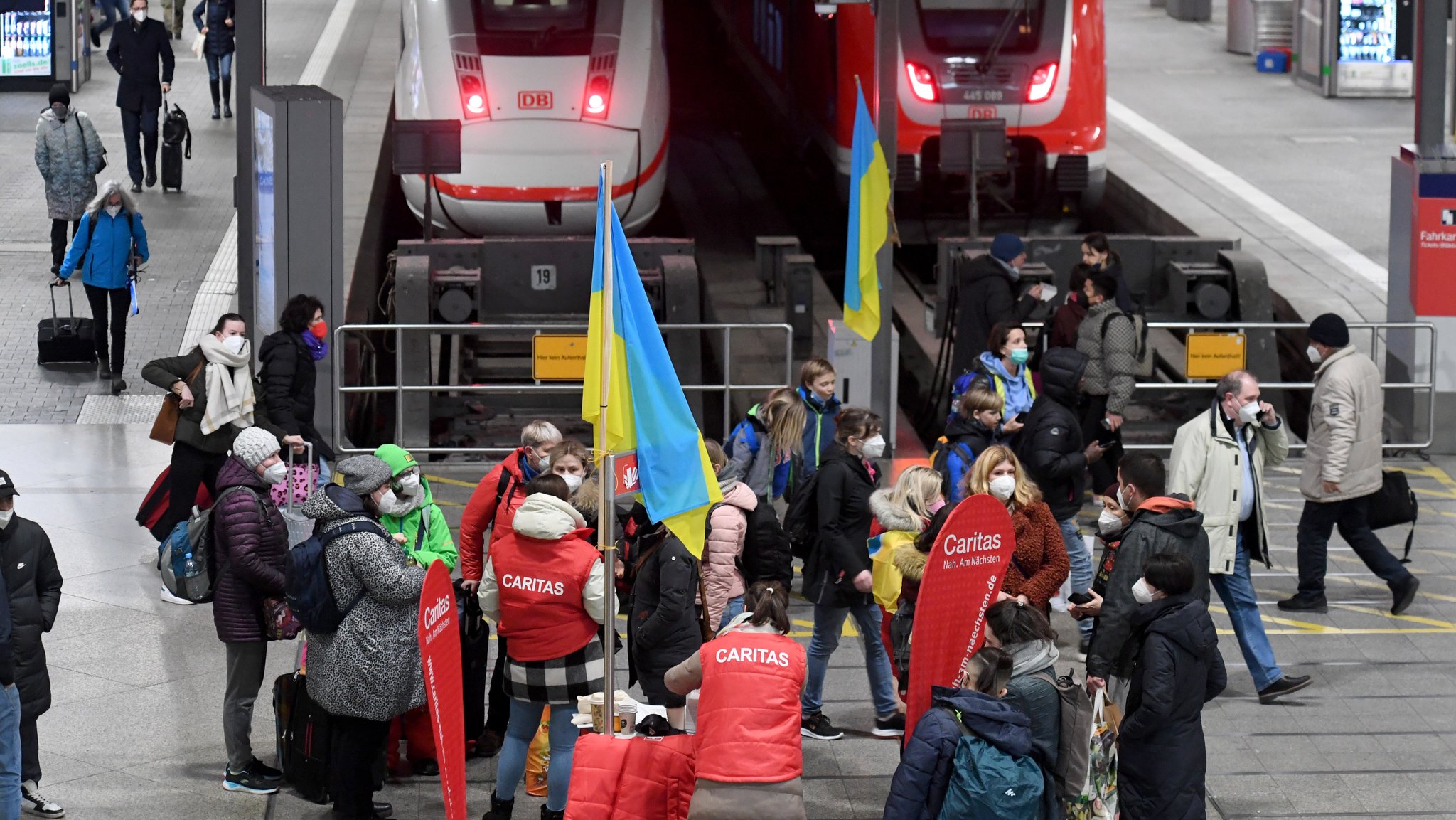 Mitarbeiter der Caritas stehen am Münchner Hauptbahnhof um Frauen und Männer aus der Ukraine zu empfangen.