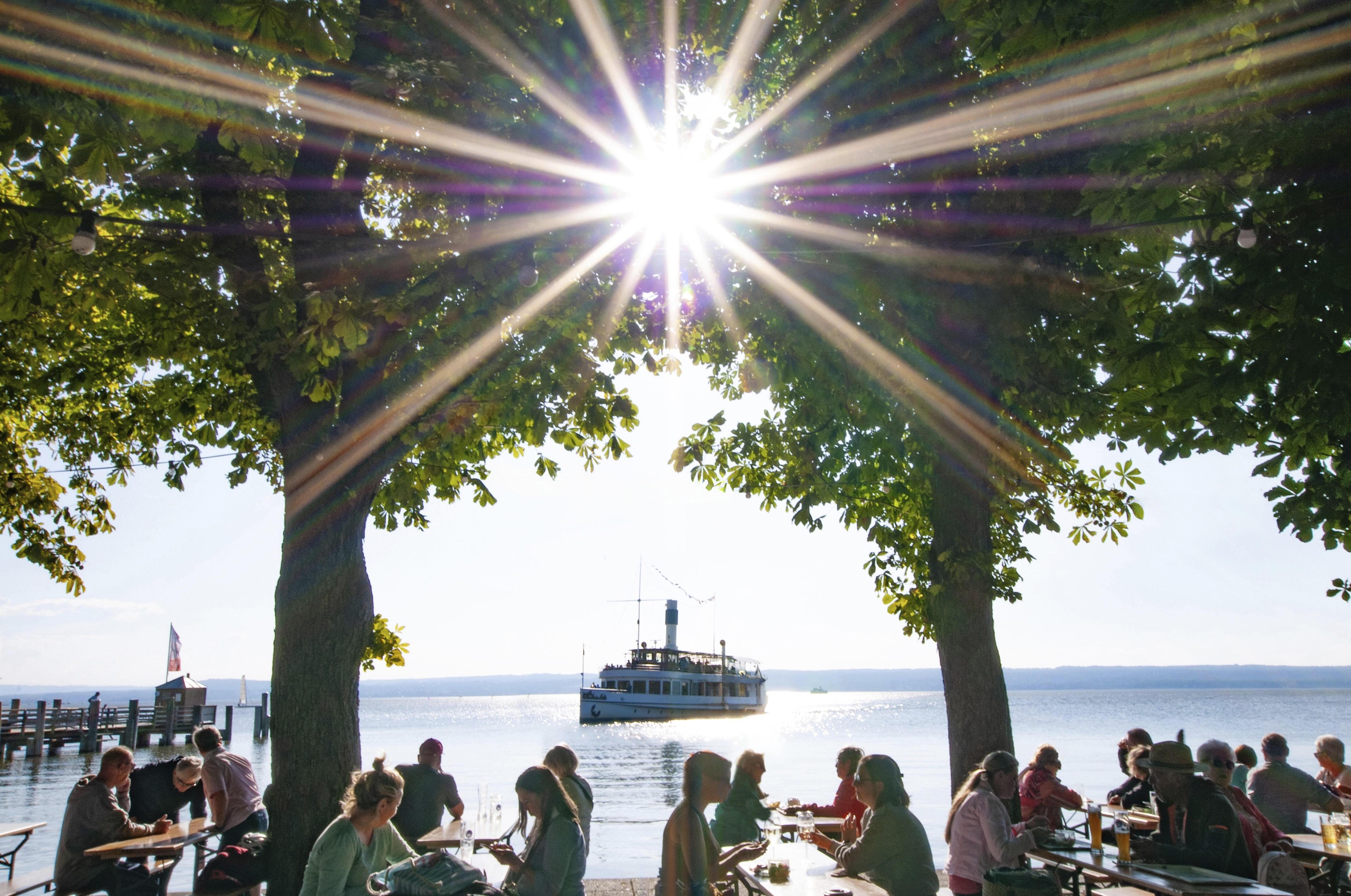 Menschen im Biergarten unter Kastanienbäumen in Herrsching am Ammersee.