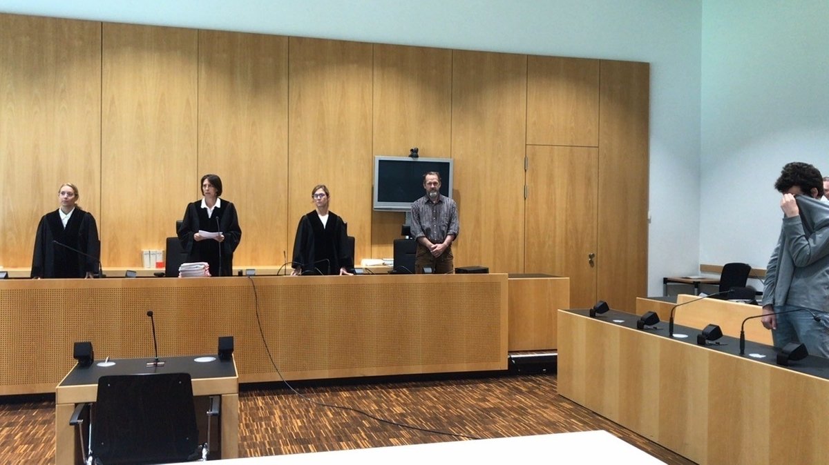 Richter und Angeklagter stehen im Gerichtssaal. 