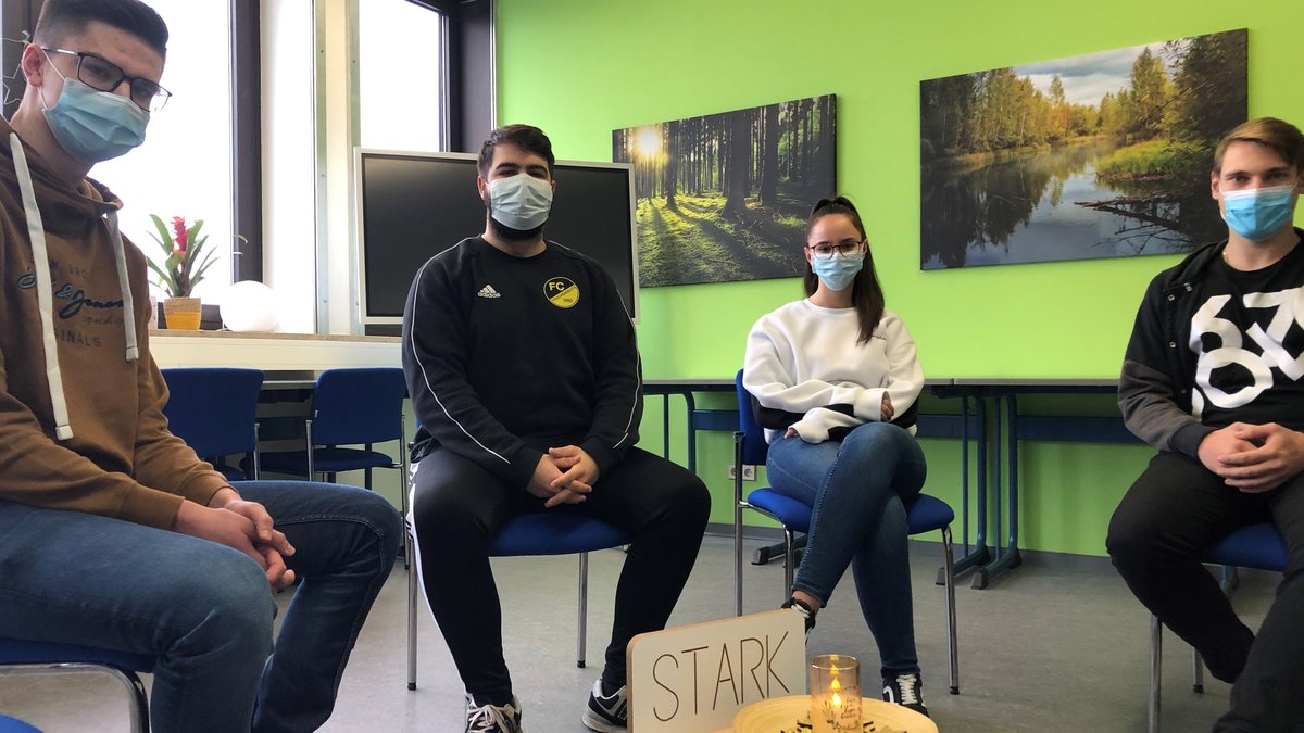 Schüler am Schulzentrum Wiesau sitzen im Kreis um eine Kerze und ein Schild mit der Aufschrift "Stark"