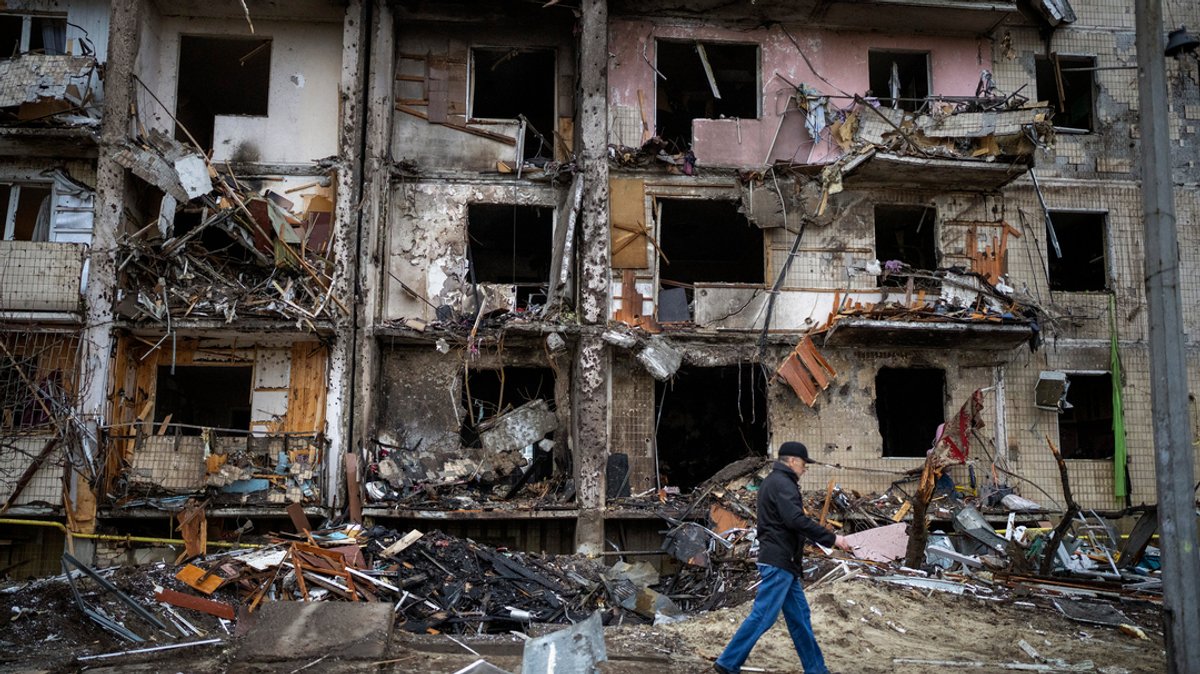 Ukraine, Kiew: Ein Mann geht an einem Gebäude vorbei, das nach einem Raketenangriff beschädigt wurde. Russische Truppen haben am Donnerstag, 24.02.2022, den erwarteten Angriff auf die Ukraine gestartet