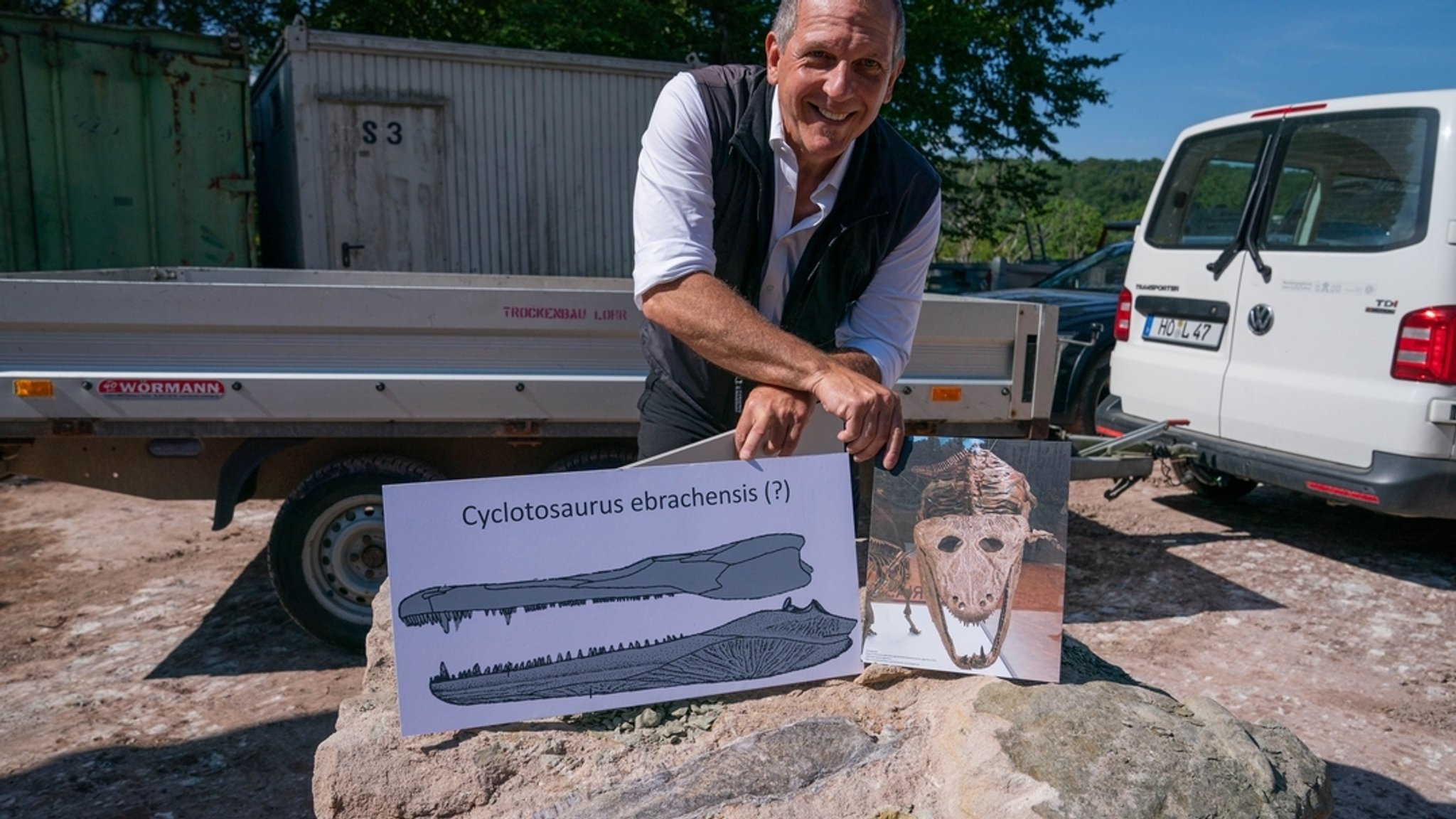 Der Leiter der Abteilung Geologischer Dienst des Landesamtes für Umwelt (LfU) Hof, Roland Eichhorn, präsentiert eine Grafik eines Cyclotosaurus neben dem auf dem Felsbrocken erkennbaren, gefundenen Unterkieferkochen eines Cyclotosaurus. In einem Steinbruch im Steigerwald ist der Unterkiefer eines ca. 230 Millionen Jahren alten Cyclotosaurus gefunden worden. 