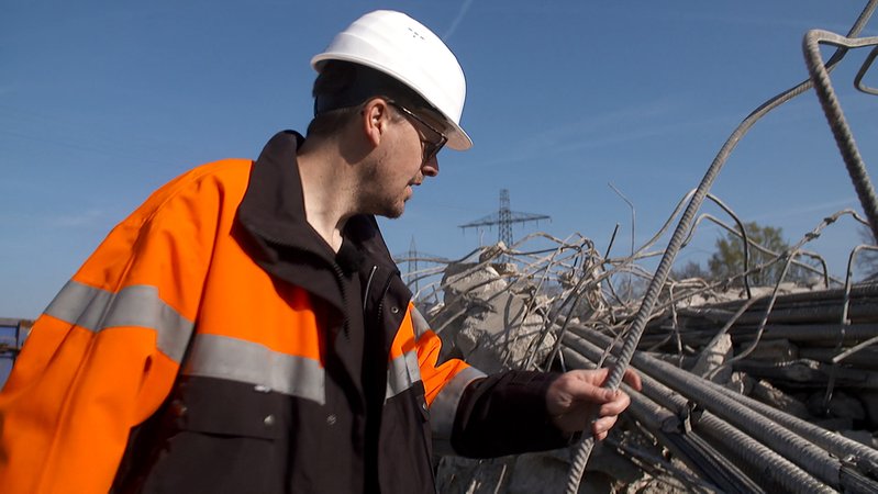 Ein Bauarbeiter untersucht den Stahl aus einer Brücke in Nürnberg. | Bild: BR Ein Bauarbeiter untersucht den Stahl aus einer Brücke in Nürnberg.