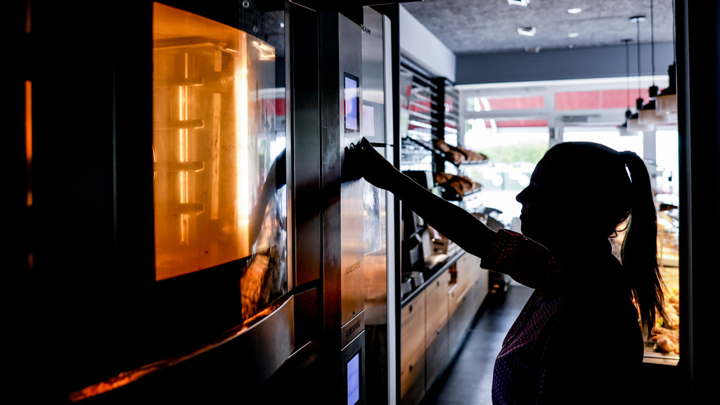 Mitarbeiterin einer Bäckerei öffnet einen Backofen