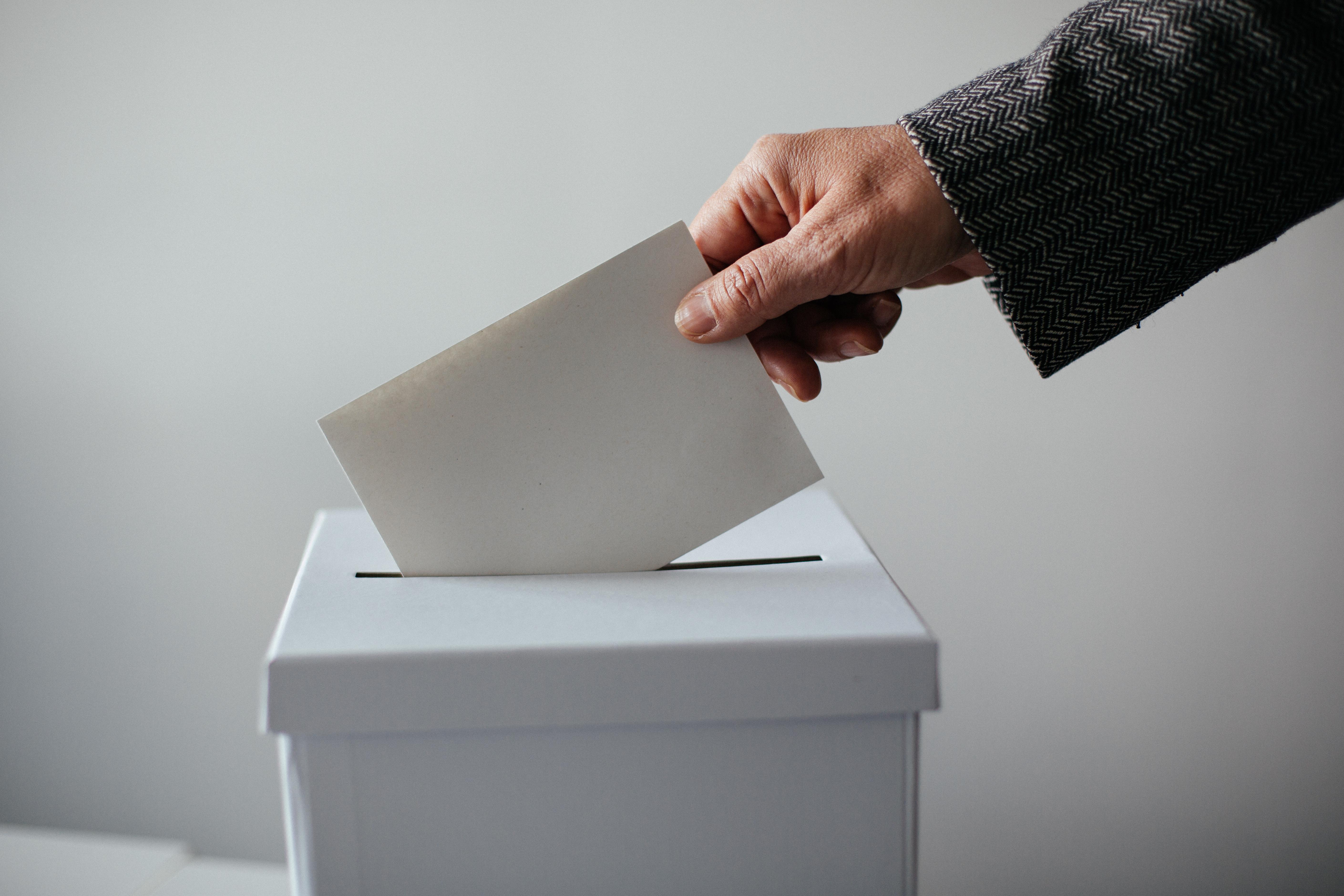Ein Mensch wirft einen Wahlschein in eine Wahlurne (Symbolbild)