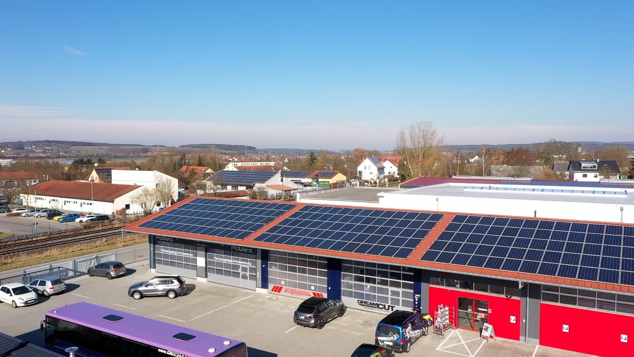 Halle mit großflächiger Solaranlage. Daneben eine Halle auf der noch Platz wäre für eine Solaranlage