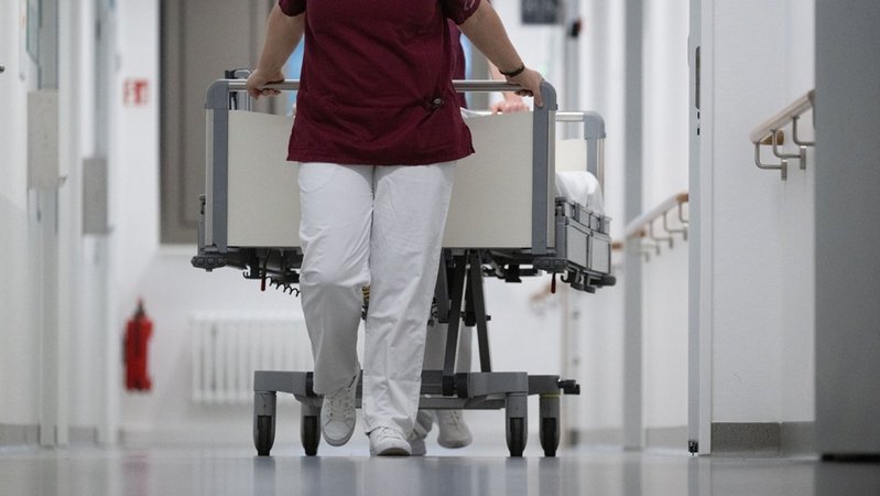 Ein Mensch zieht ein Krankenhausbett hinter sich her. | Bild: dpa-Bildfunk/Marijan Murat Ein Mensch zieht ein Krankenhausbett hinter sich her.