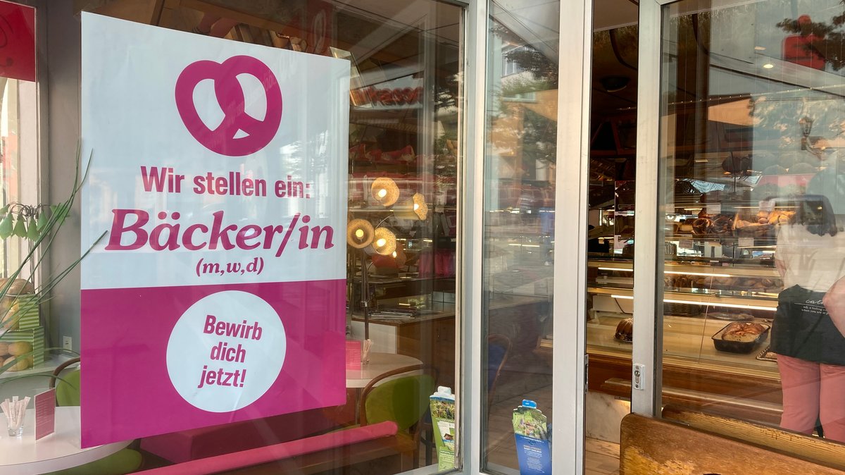 An der Eingangstür der Bäckerei hängt ein Plakat: "Wir stellen ein: Bäcker/in".