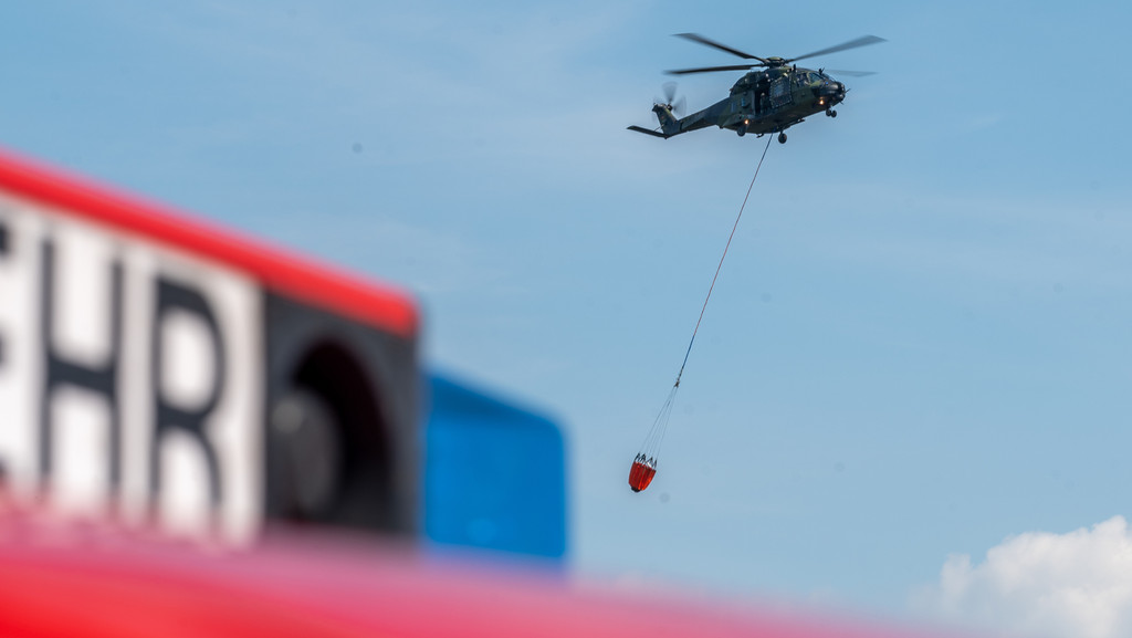 Ein Transporthubschrauber der Bundeswehr vom Typ NH90 fliegt mit seinen Löschwasserbehälter vom Typ Bambi Bucket während einer Übung zum betanken.