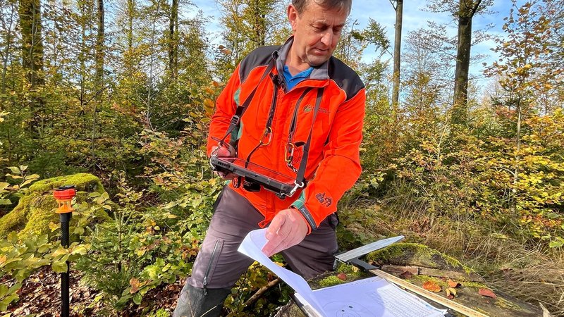 Ein Mann in orangener Jacke blättert in seinen Unterlagen | Bild: BR/Richard Padberg Ein Mann in orangener Jacke blättert in seinen Unterlagen