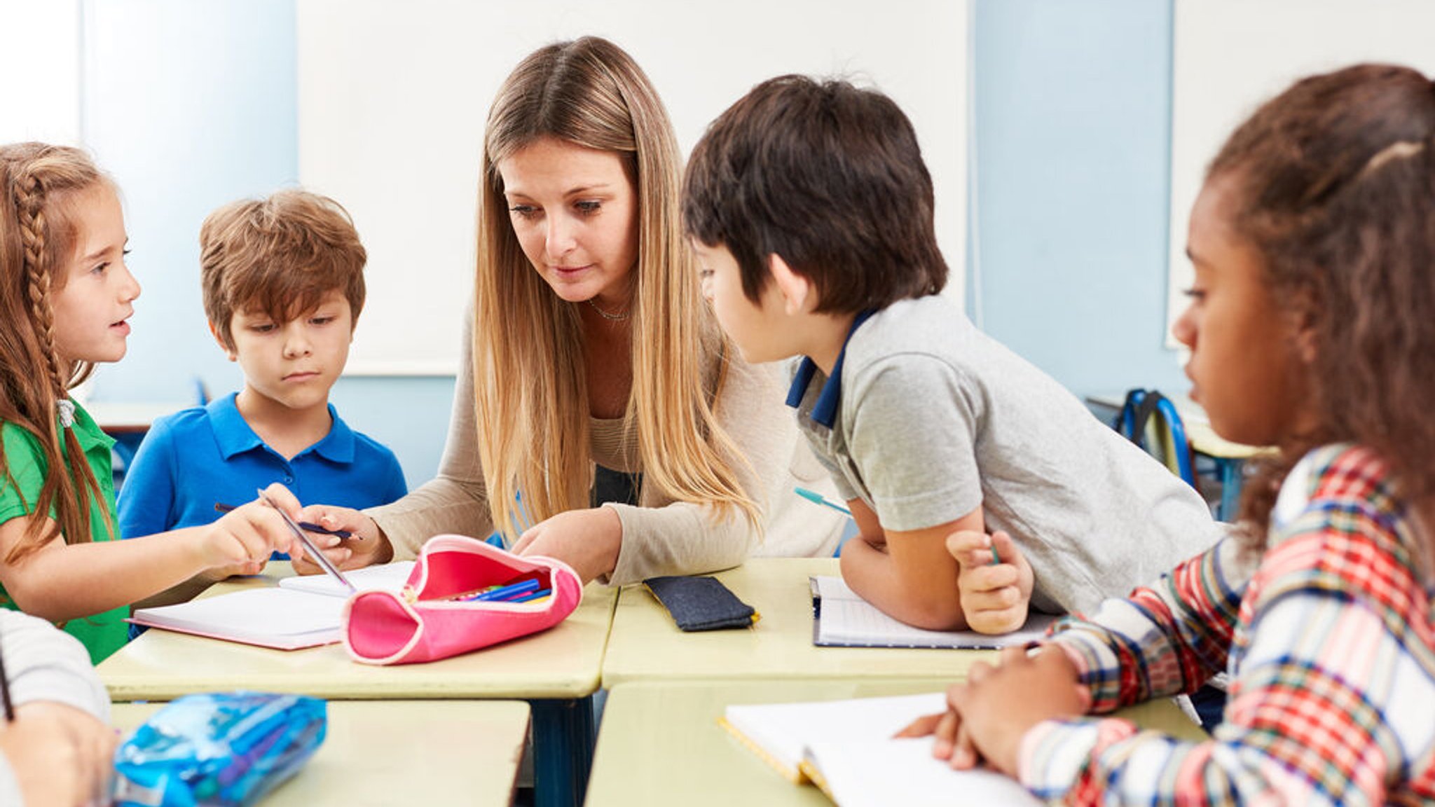 Eine junge Frau hilft Kindern bei ihren Aufgaben. | Bild: stock.adobe.com/Robert Kneschke Eine junge Frau hilft Kindern bei ihren Aufgaben.