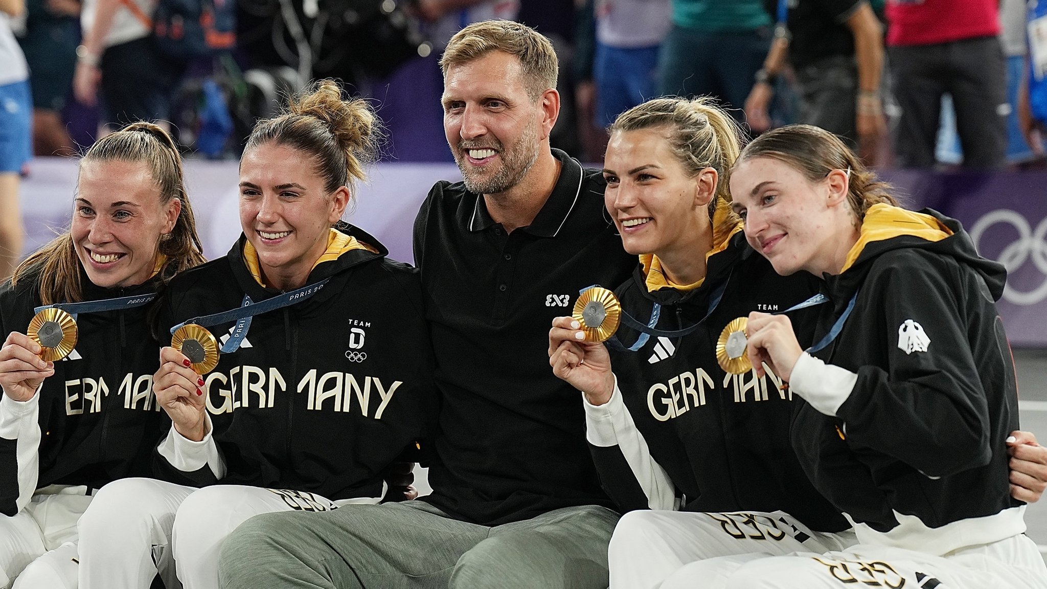 ARCHIV - 05.08.2024, Frankreich, Paris: Olympia, Paris 2024, 3x3 Basketball, Damen, Finale, Deutschland - Spanien, Finalrunde, Place de la Concorde, der ehemalige NBA-Star Dirk Nowitzki feiert mit die Goldmedaillengewinnerinnen Svenja Brunckhorst (l-r), Marie Reichert, Sonja Greinacher und Elisa Mevius nach der Siegerehrung. (zu dpa: «Excel und Abwärtstrend: Deutscher Sport im Olympia-Tief») 