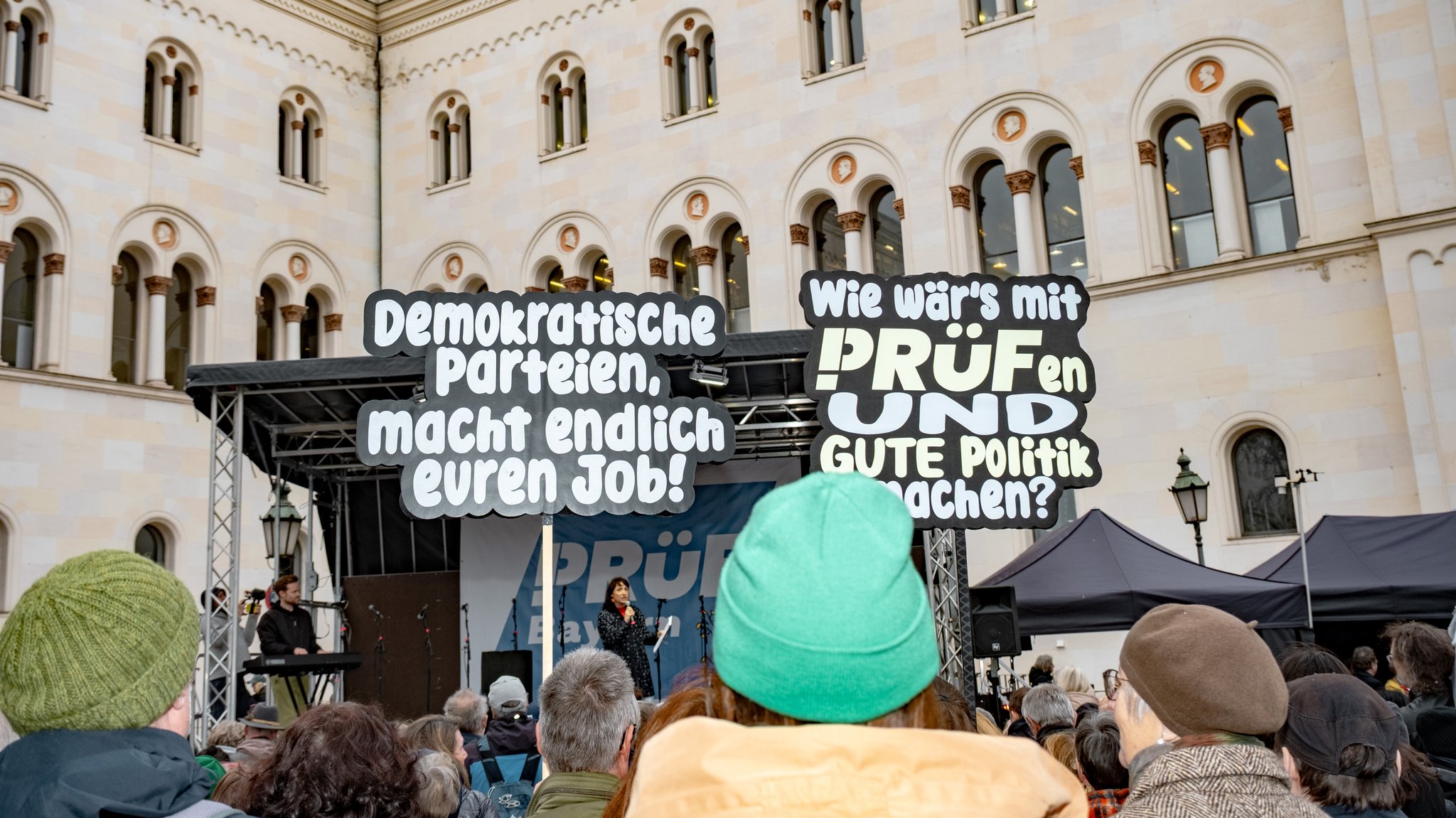 Menschen halten bei der Demo in München Schilder hoch 